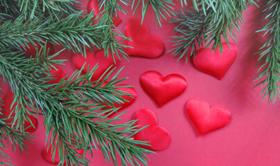 natural branches of a christmas tree and blured red hearts on a red background , copy space