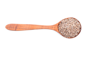 Wooden spoon over the pile of cumin seeds isolated over the white background