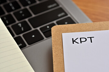 A piece of paper with the word "KPT" written on it sits on the keyboard. That's an acronym for "Keep, Problem, Try".
