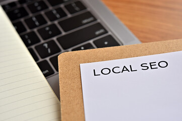 A piece of paper with the word "LOCAL SEO" written on it sits on the keyboard. Close up.
