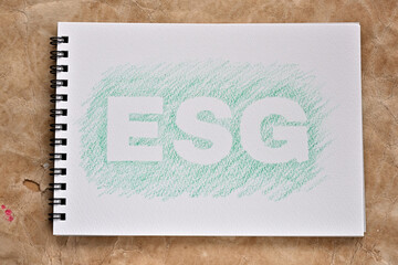 There is a sketchbook with the word "ESG" stenciled on it. It is an acronym that stands for environmental, social and governance.