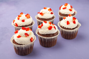 Delicious tasty chocolate muffins with strawberry on lilac background