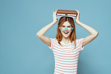 Female student with books on her head science education blue background emotions gesturing with...