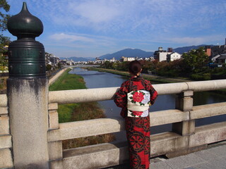 An Asian woman wearing a traditional Japanese kimono looking at the Kamo River, Kyoto, Japan