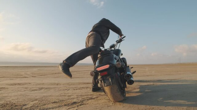 Motorcyclist doing tire burnout in the desert, slow motion. Professional motorcyclist drift on sport bike on a dry salt lake and ride away