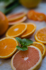 Fototapeta na wymiar rodajas de distintos tamaños de naranja pomelo quinoto y menta sobre base blanca fruta de estacion primavera verano cordoba argentina