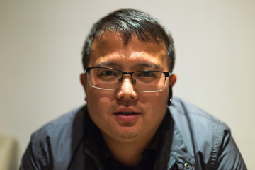 portrait of tired young man sitting on sofa after hard work and bluetooth earphone in his ears