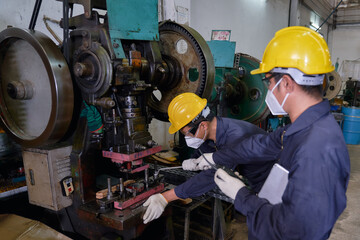 Two engineers repair heavy machine with wrench for safety work