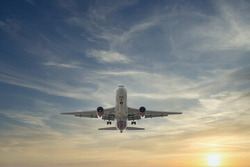 Naklejka na ściany i meble Airplane approaching with beautiful sunset in dramatic sky