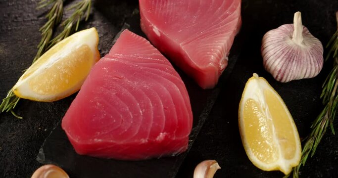 Pieces of raw tuna with lemon and garlic on the table.