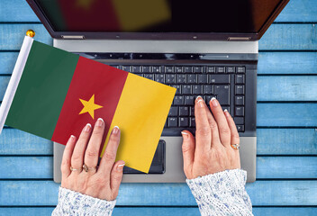 woman hands and flag of Cameroon on computer, laptop keyboard 