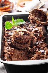 Chocolate icecream in metal tray with mint leaf and almond nuts