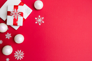 Gift boxes wrapped in white wrapping paper and white Christmas decorations on a red background. Christmas and New Year concept