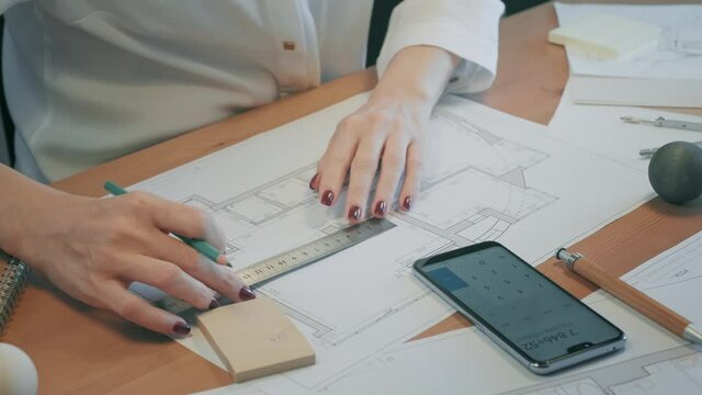 Young pretty engineer, architect or designer woman works with drawings in office