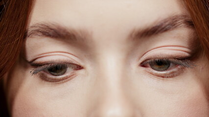 Gorgeous female grey eyes blinking indoors. Woman face on videotaping in atelier