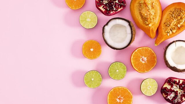 Slices of fresh ripe fruits appear on right side of pastel pink theme. Stop motion 