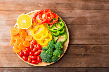 Top view of fresh organic fruits and vegetables in plate wood (carrot, Broccoli, tomato, orange, Bell pepper) on wooden table, Healthy lifestyle diet food concept