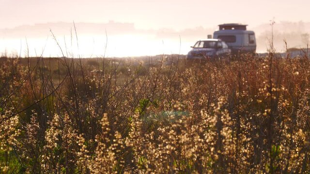 Coastal landscape with caravan trailer wild camping on beach. Capi Corb, Mediterranean coast of Spain. Holidays, traveling with motorhome. Focus on grass