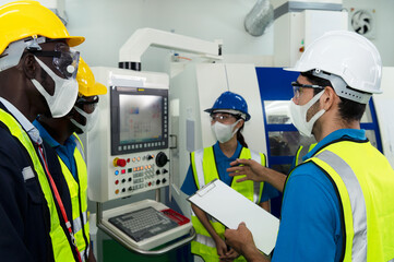 Male technician supervisor discuss with a group of factory technicians in factory with protective...