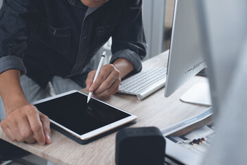 Man interior designer or decorator using stylus pen on digital tablet working on desktop computer in modern office