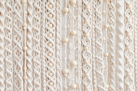 Close-up of hand made macrame texture pattern. Eco friendly modern knitting. Natural decoration concept in the interior. Handmade macrame wall hanging 100% cotton and wooden beads