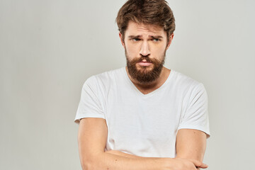 Fototapeta premium A man in a white t-shirt with a beard emotions displeased facial expression light background