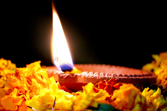 Marigold flowers around Clay Oil Lamp or Diwali Diya, over white background. selective focus