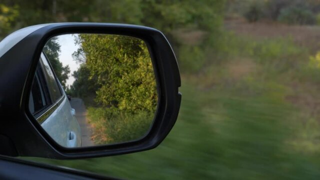 4K video of driving car on forest road, closeup front mirror view reflaction
