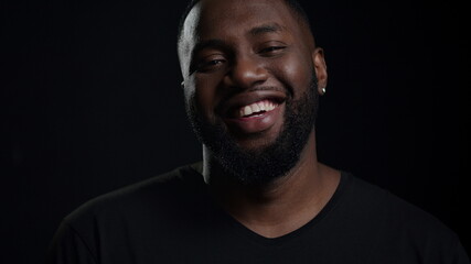 Obraz premium Smiling african man looking at camera indoors. Afro guy making smile in studio