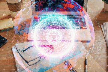 Computer on desktop in office with technology theme hologram. Double exposure. Tech concept.