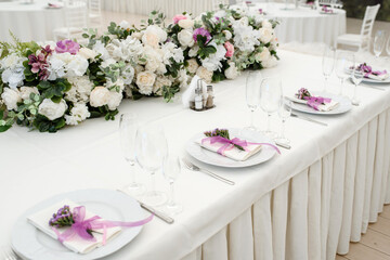 party reception table decorated with flowers: plates, forks, knives and wine glasses.