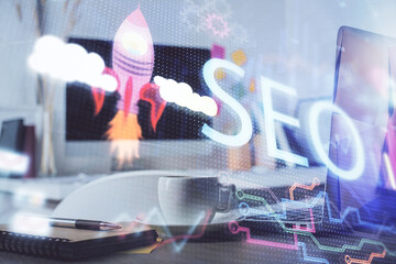 Double exposure of table with computer and seo drawing hologram. Search optimization concept.