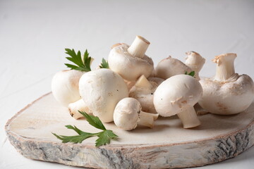 Fresh white champignon mushrooms on wooden board