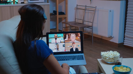 Freelancer having virtual conversation with colleagues on laptop sitting on couch in pijamas. Remote worker discussing during online meeting consulting with team on videocall using internet technology