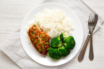 Homemade Chicken Breast, Rice and Broccoli on a white plate on a white wooden surface, top view....