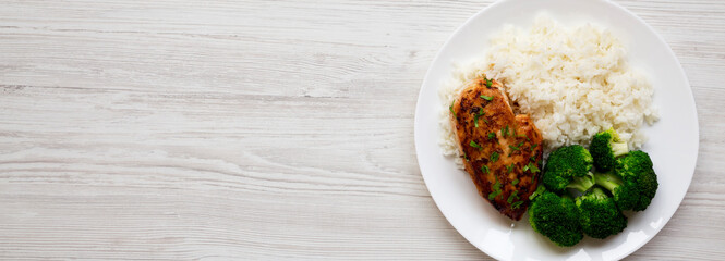 Homemade Chicken Breast, Rice and Broccoli on a white plate on a white wooden background, top view. Flat lay, overhead, from above. Copy space.