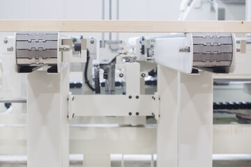 Glued laminated timber lies on the conveyor belt of a woodworking machine. Automated line. Constructional building materials made of wood. Woodworking industry concept.