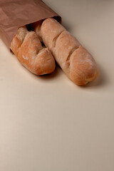 top view of french baguettes in paper bag and wheat on light table top