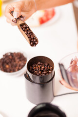 Woman putting coffee beans in grinder in the morning. Housewife at home making fresh ground coffee in kitchen for breakfast, drinking, grinding coffee espresso before going to work