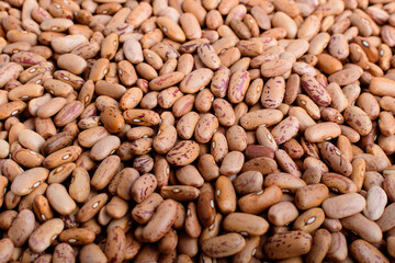 Natural background of many fresh organic red beans in a plastic box in warm light, top view or flat lay of organic vegan food photographed with soft focus.