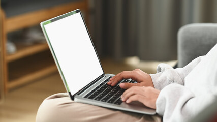 Cropped shot of young woman sitting on a couch in the living room at home and using laptop.