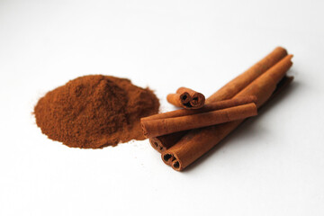 Loose cinnamon and cinnamon sticks on a white background. Cinnamon is used primarily for spices, imparting a spicy aroma to foods