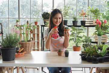 Happy young Asian female wearing apron uniforms gardening, watering and take care of plants at home