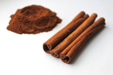 Loose cinnamon and cinnamon sticks on a white background. Cinnamon is used primarily for spices, imparting a spicy aroma to foods