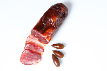 Acorn-fed Iberian loin with three slices cut, garnished with three acorns and with a white background viewed from above