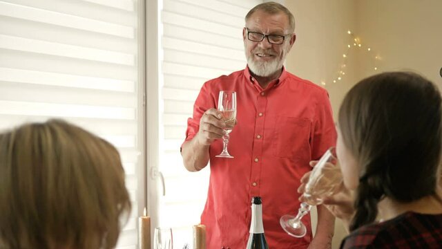 Happy Family Celebrating Christmas Together. Traditional Festive Christmas Dinner In Multigenerational Family. An Older Family Member Makes A Toast.