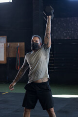 Chico con mascarilla en un gimnasio realizando Cross training con mancuernas