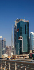Fototapeta na wymiar Skyscrapers in district of Dubai city known as Business Bay. Tallest building in the world, Burj Khalifa can be seen on the background. UAE.