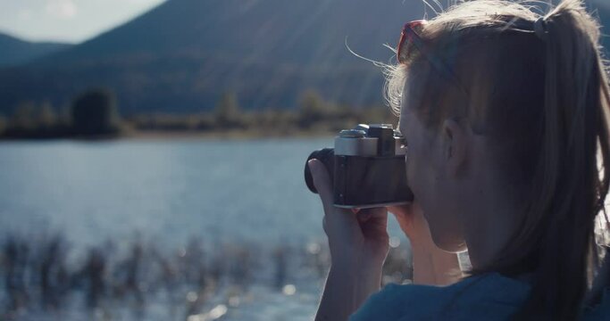Photographer woman take analog photo autumn travel at lake lens flare