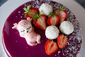 Appetizing mousse cake covered with pink icing, decorated with a figurine of a white chocolate deer and berries. view from above